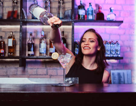 A beautiful girl bartender prepares an alcoholic cocktail with vodkaの写真素材