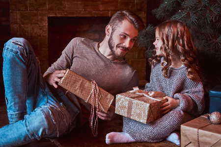 Love, family, fatherhood, Christmastime. Happiness father and his cute little daughter sitting on the floor surrounded by giftsの写真素材