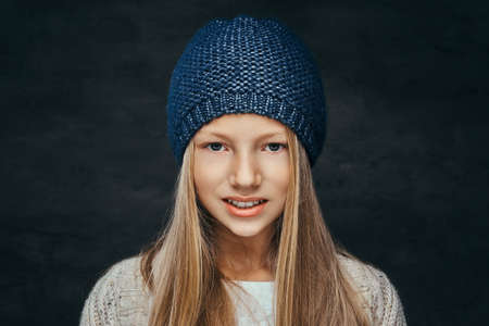Portrait of a smiling teen girl with blonde hair wearing a winter hat and sweaterの写真素材