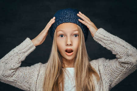 Portrait of a surprised teen girl with blonde hair wearing a winter hat and sweaterの写真素材