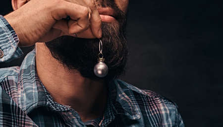 A bearded man wearing a checkered shirt holding a small christmas toy in the background of his face.の写真素材