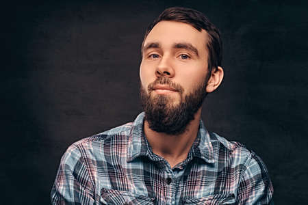 A bearded man wearing a checkered shirt.