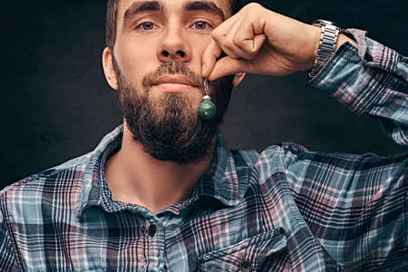 A bearded man wearing a checkered shirt holding a small christmas toy in the background of his face.