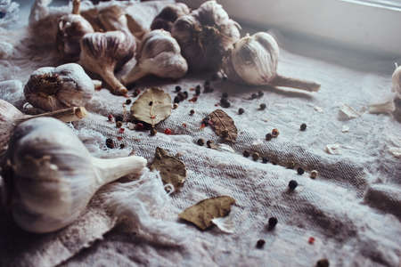 Photo of the fruits of black pepper, bay leaves, garlic scattered on a fabric sheetの写真素材