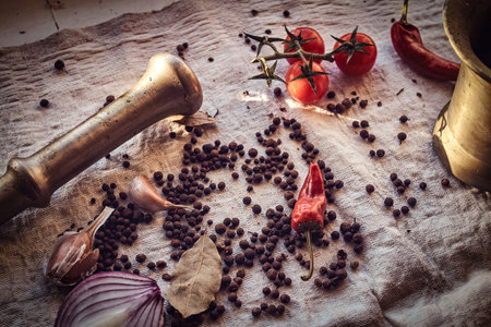 Close-up photo of the fruits of black pepper, red pepper, cherry tomatoes and garlic on linen fabricの写真素材
