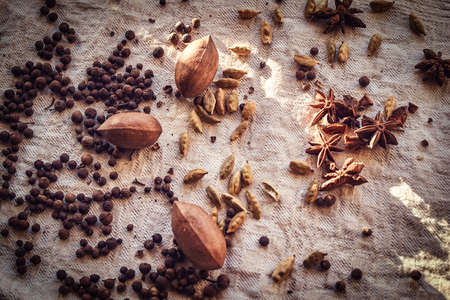 Close-up photo. Black peppercorn, beans, cinnamon, pecan on linen fabric.の写真素材