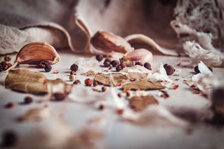 Photo of the fruits of black pepper, bay leaves, garlic scattered on a fabric sheet