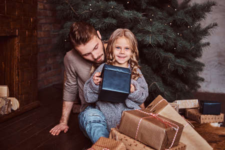 Happiness father and his cute little daughter open gifts while sitting on the floorの写真素材