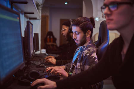 Team of teenage gamers plays in a multiplayer video game on pc in a gaming club.