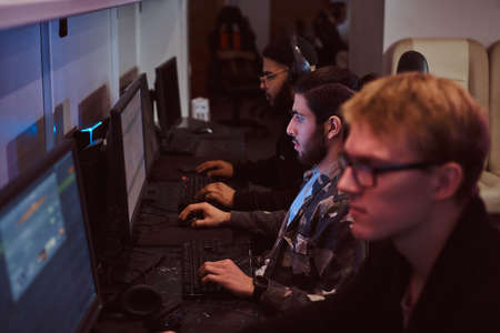 Team of teenage gamers plays in a multiplayer video game on pc in a gaming club.の写真素材
