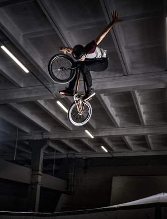 Young BMX making crazy tricks on his bicycle in skatepark indoors. Bmx freestyle.の写真素材