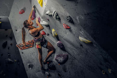 Young sporty woman climbing artificial boulder indoors.の写真素材