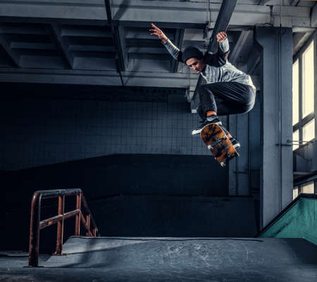 Skateboarder jumping high on mini ramp at skate park indoor.の写真素材