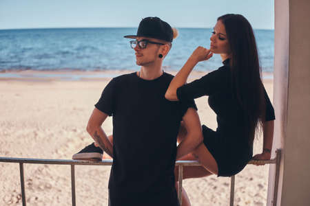 Young couple in love on vacation at the seaside, enjoy spending time together, the girl sits on the...