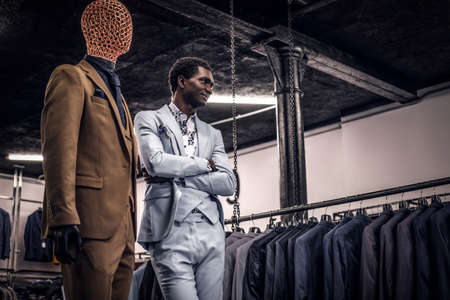 A handsome well-dressed African-American man posing with crossed arms in a classic menswear store.の写真素材