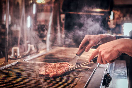 Close-up image of a cooking delicious meat steak on a grill in a restaurant kitchen.の写真素材