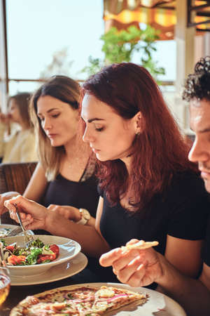 Young friends enjoying pizza and salad in a outdoor cafe
