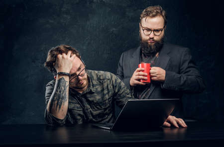 Two programmers are thinking hard, trying to find a solution to the problem in office against the background of the dark wallの写真素材