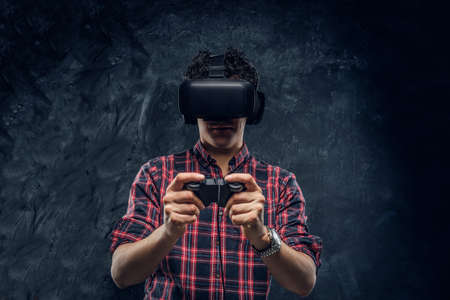 Teenager plays the game wearing virtual glasses on a black background in the studioの写真素材