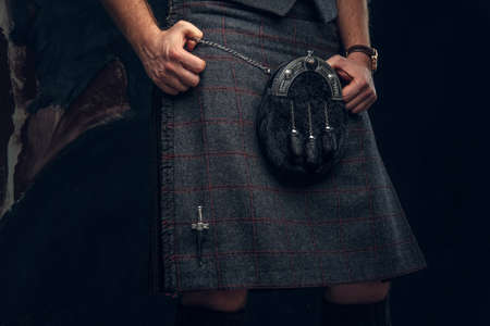 Traditional Scottish costume. Kilt and sporran. Studio photo against a dark textured wallの写真素材