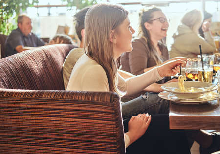 Food and people concept. Young friends enjoying food and having fun together in the restaurant or...