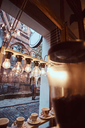 The interior of the coffee shop with overlooks the beautiful old building, showcase decorated with lamps and dishes, inside viewの写真素材