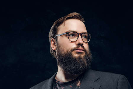 Close-up portrait of a smart bearded man in glasses in a dark studio