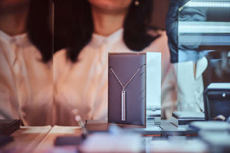Woman assistant shows the exclusive gold necklace in the luxury jewelry store