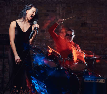 Jazz band performance. Beautiful singer in elegant dress and drummer in a nightclub