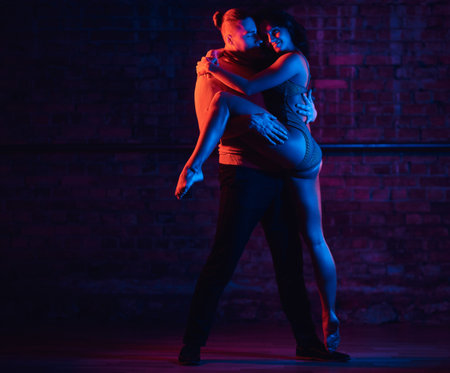 Young attractive couple dancing on the dance floor in a night club. Dancers performing in the dark...