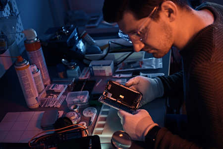 The technician carefully examines the integrity of the internal elements of the smartphone in a...