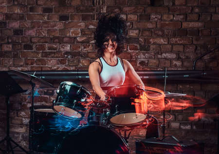 Beautiful young girl musician playing on drums and cymbals. Live music in a night club
