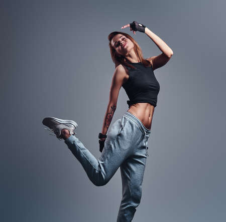 Full-length portrait of a slim fitness girl wearing sportswear posing in a studio. Isolated on a...