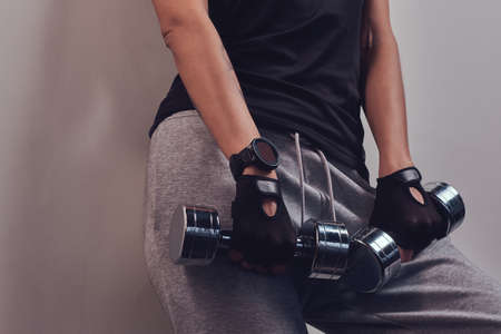 Fashion, sport, health. Fitness woman wearing sportswear posing with dumbbells. Studio portrait on a...