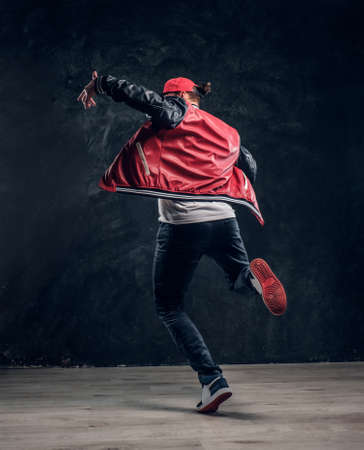 Stylish guy performs breakdance acrobatic elements. Studio photo against a dark textured wallの写真素材