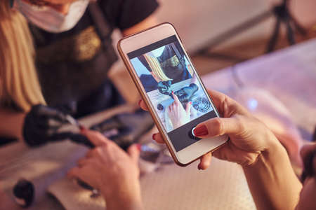 Young woman takes a photograph of the manicure procedure in the beauty salonの写真素材