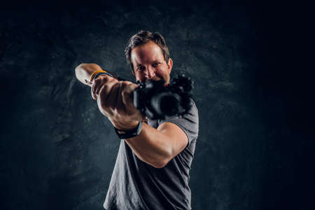 Crazy middle-aged man dressed in casual clothes holding an assault rifle and aims at the target....
