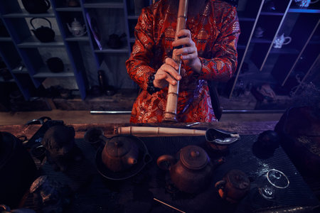 Chinese tea ceremony. Tea master in kimono performs in the dark room with a wooden interior, playing...
