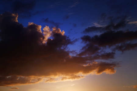 Golden sunlight and fluffy orange cloud on the blue sky an evening time.