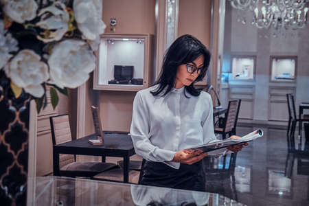 Attractive elegant woman is watching magazine at posh jewellery boutique.の写真素材