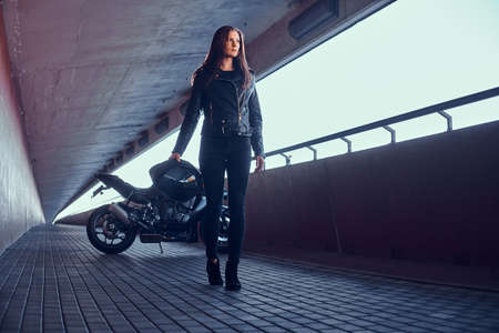 Beautiful pensive woman is standing in tunnel with her bike and helmet.