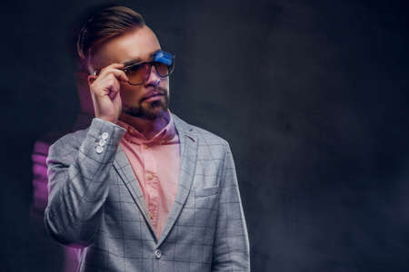 Movement photo of attractive smart man in checkered blaze, sunglasses and pink shirt.の写真素材
