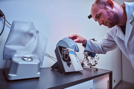 Expirienced watchmaker is doing engraving for custmers watch using special tool at his workshop.