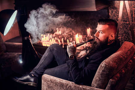 Elegant smart man is relaxing and smoking hookah after long hard day.の写真素材