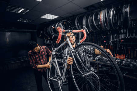 Two attractive mans are working on bicycle fixing at busy workshop.の写真素材