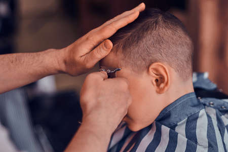 Little pretty school boy had his first trendy haircut at modern barbershop.の写真素材