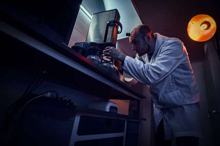 Focused watchmaker is working with autoclave at his own studio.