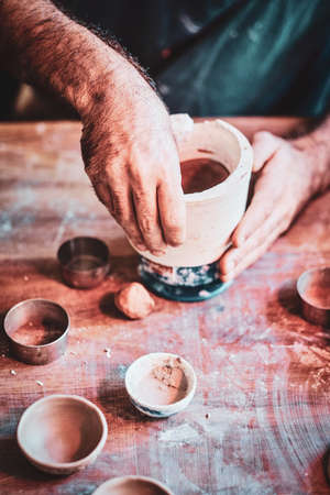 Man is putting colourful clay to his new handmade pot.の写真素材