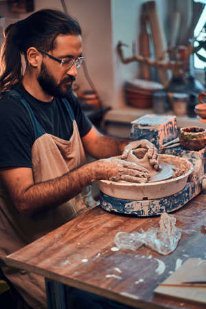 Attractive man in glasses is working on his own clay project.