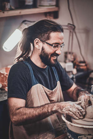 Man in glasses is working on his own clay project.